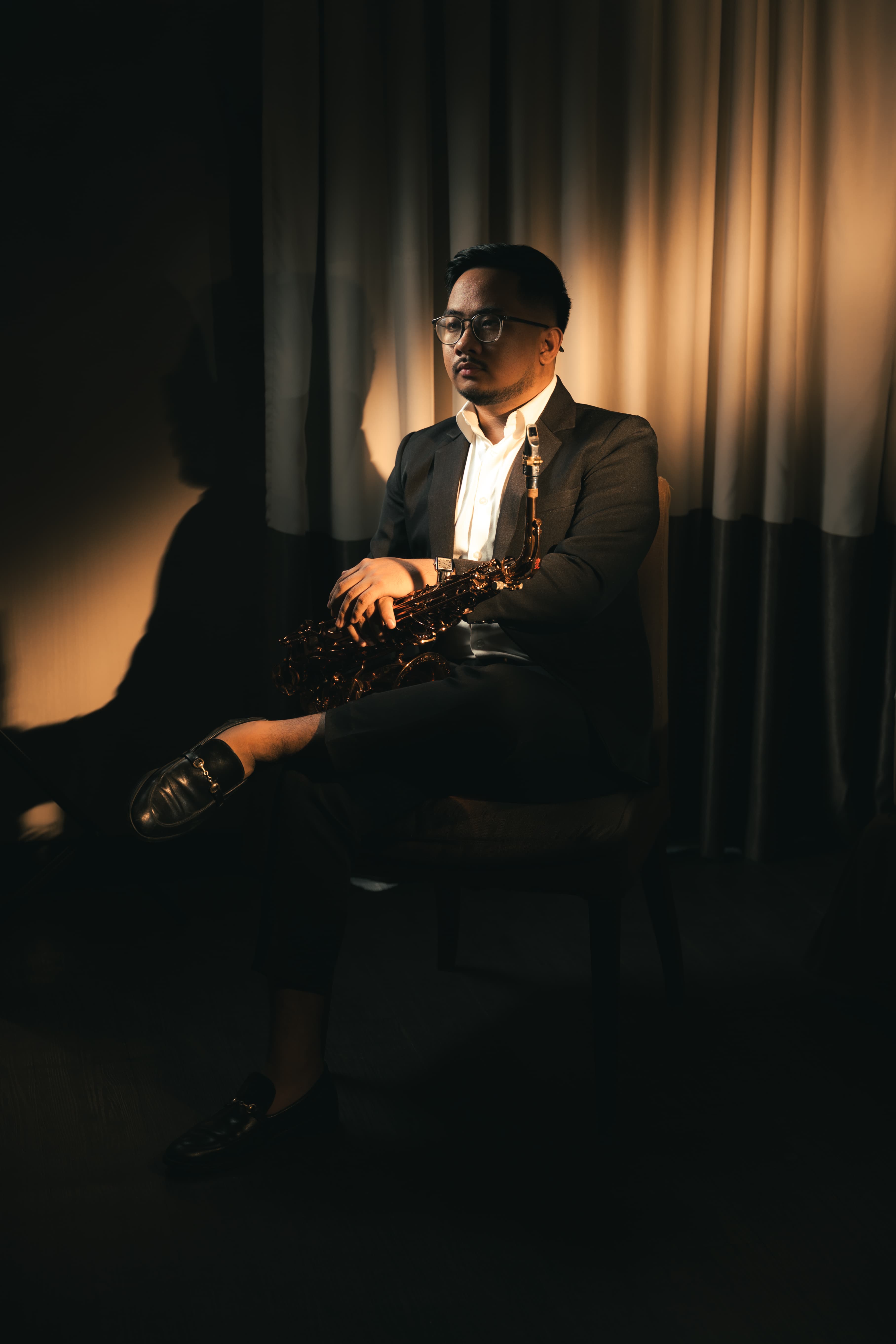 Noy Cajilig seated with saxophone in warm stage light